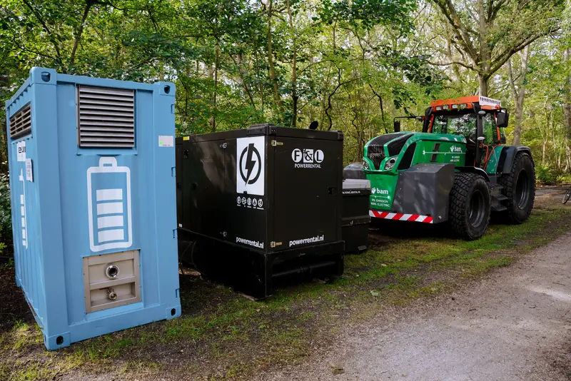 Een batterijcontainer en een elektrische trekker langs het bospad